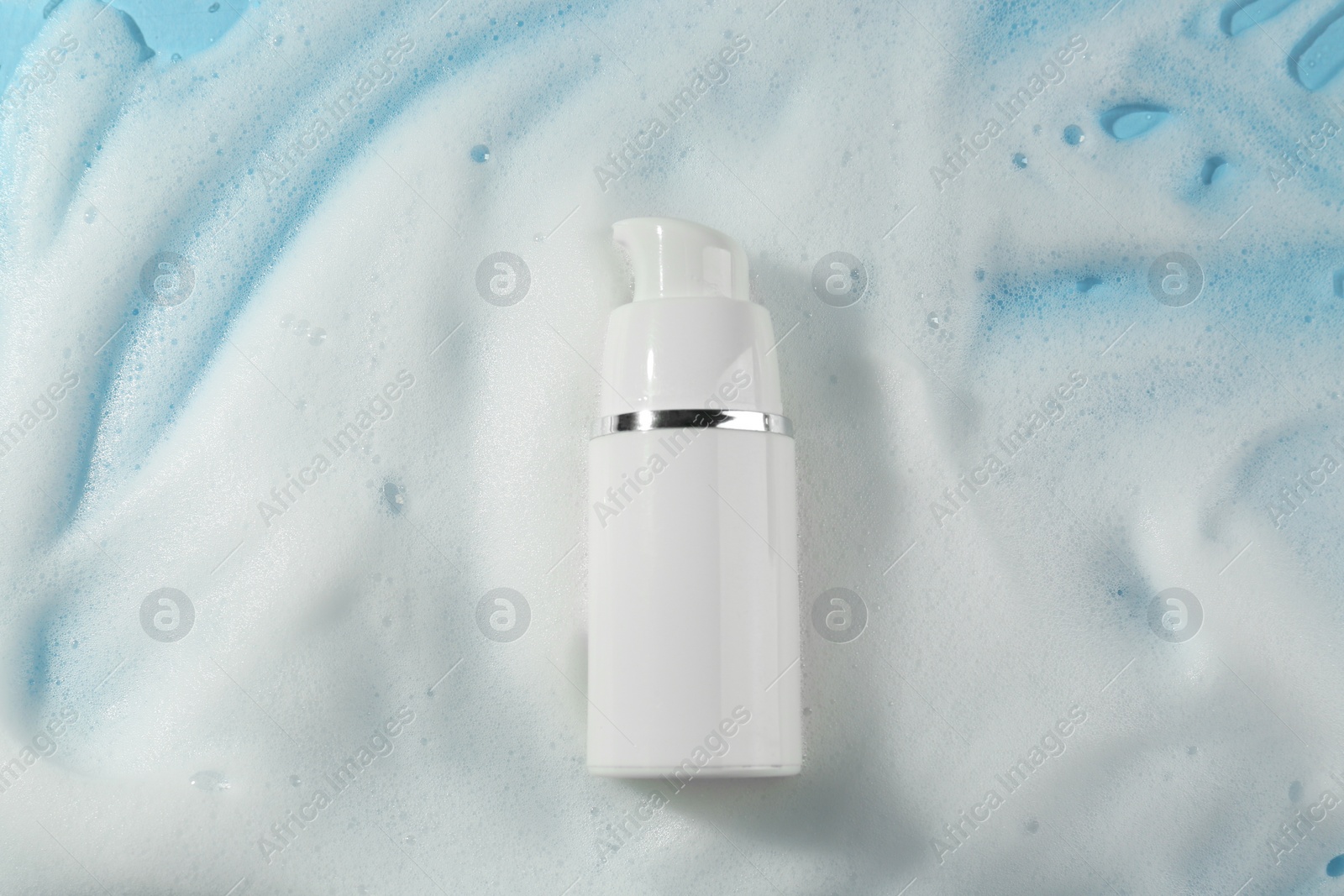 Photo of Bottle with cleansing foam on light blue background, top view. Cosmetic product