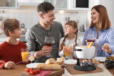 Photo of Happy family enjoying fondue dinner at home