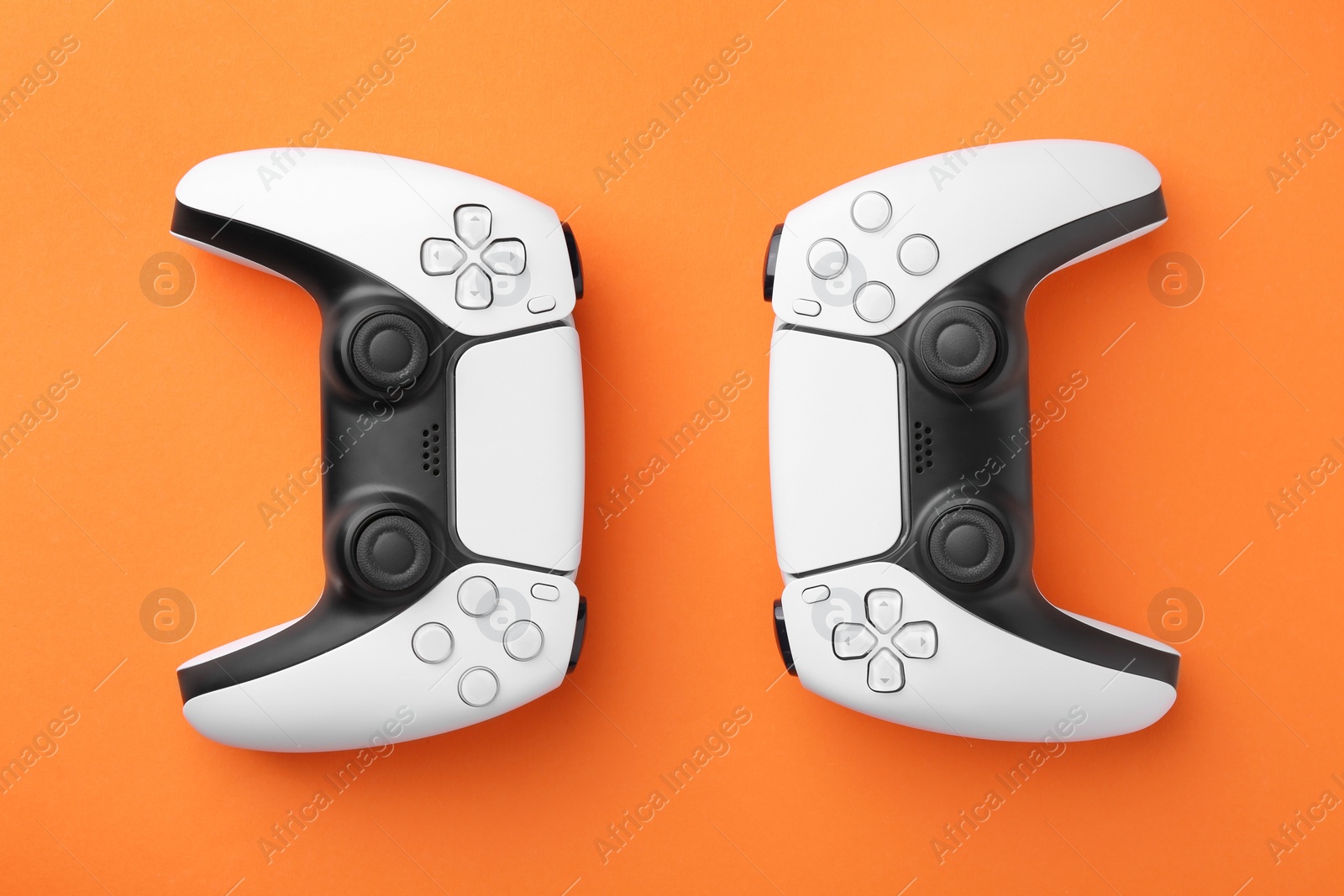Photo of Wireless game controllers on orange background, flat lay