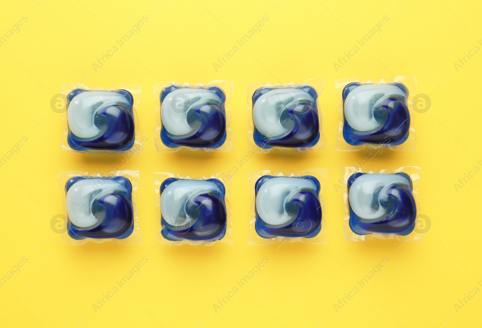 Photo of Laundry capsules on yellow background, flat lay