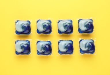 Laundry capsules on yellow background, flat lay