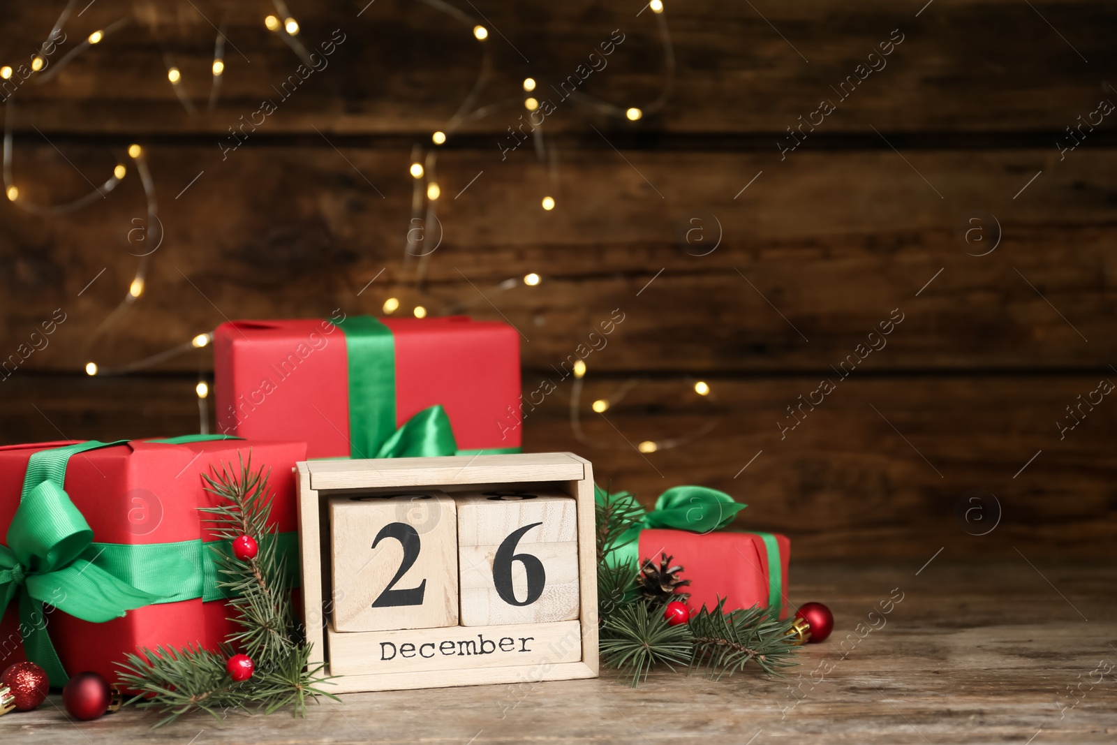 Photo of Block calendar with Boxing Day date near gifts on wooden table. Space for text