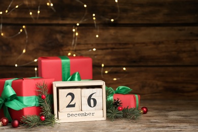 Block calendar with Boxing Day date near gifts on wooden table. Space for text