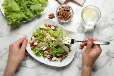 Woman with tasty pear salad at white marble table, top view