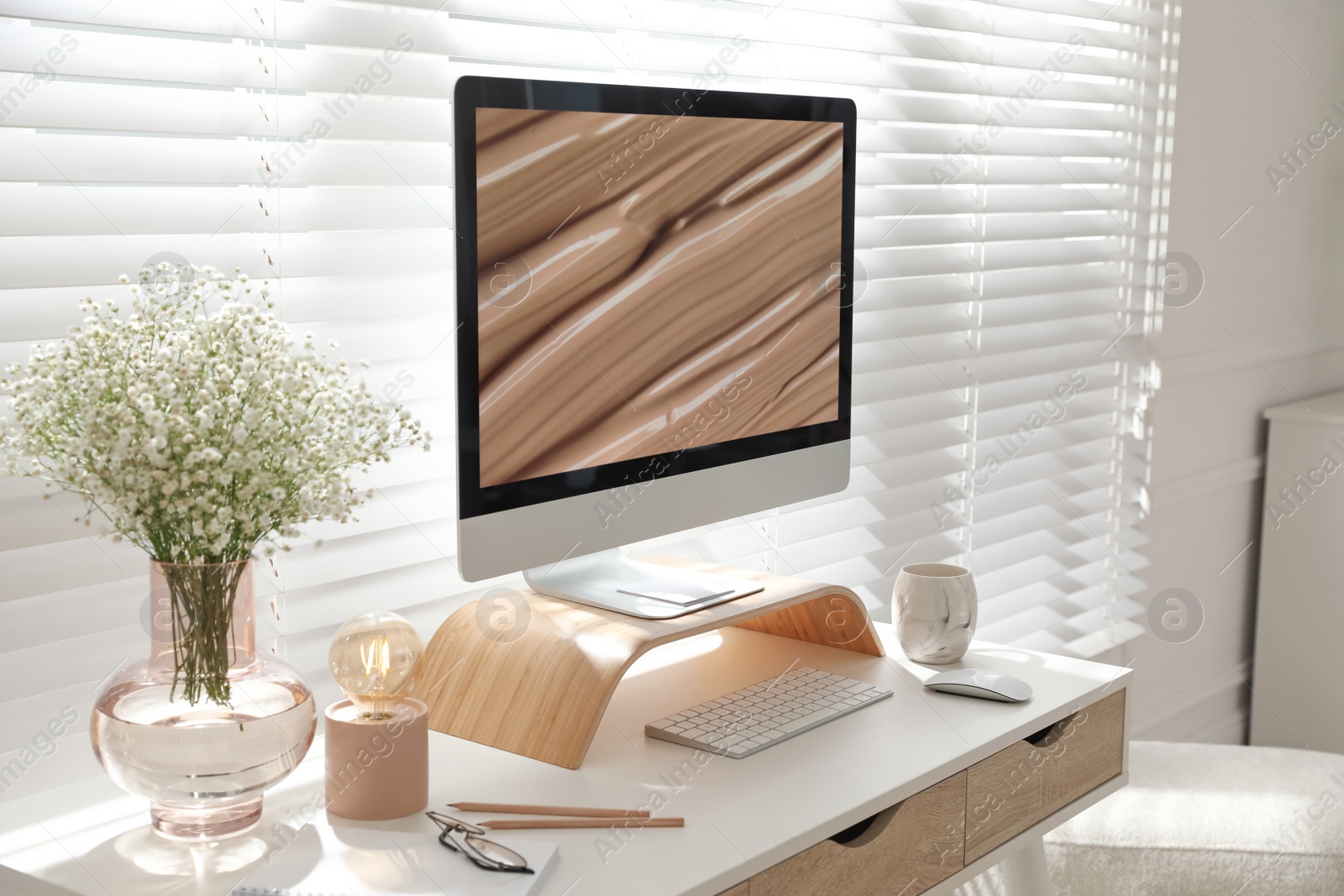 Photo of Comfortable workplace with modern computer and beautiful flowers in room. Interior design