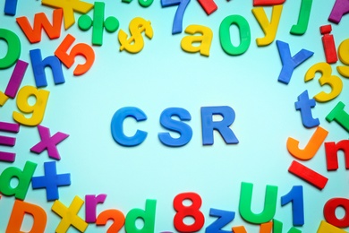 Photo of Abbreviation CSR made of plastic letters on light blue background, flat lay. Corporate social responsibility