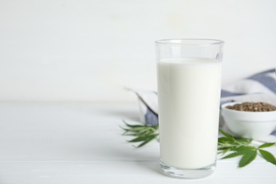 Photo of Glass of fresh hemp milk on white wooden table. Space for text