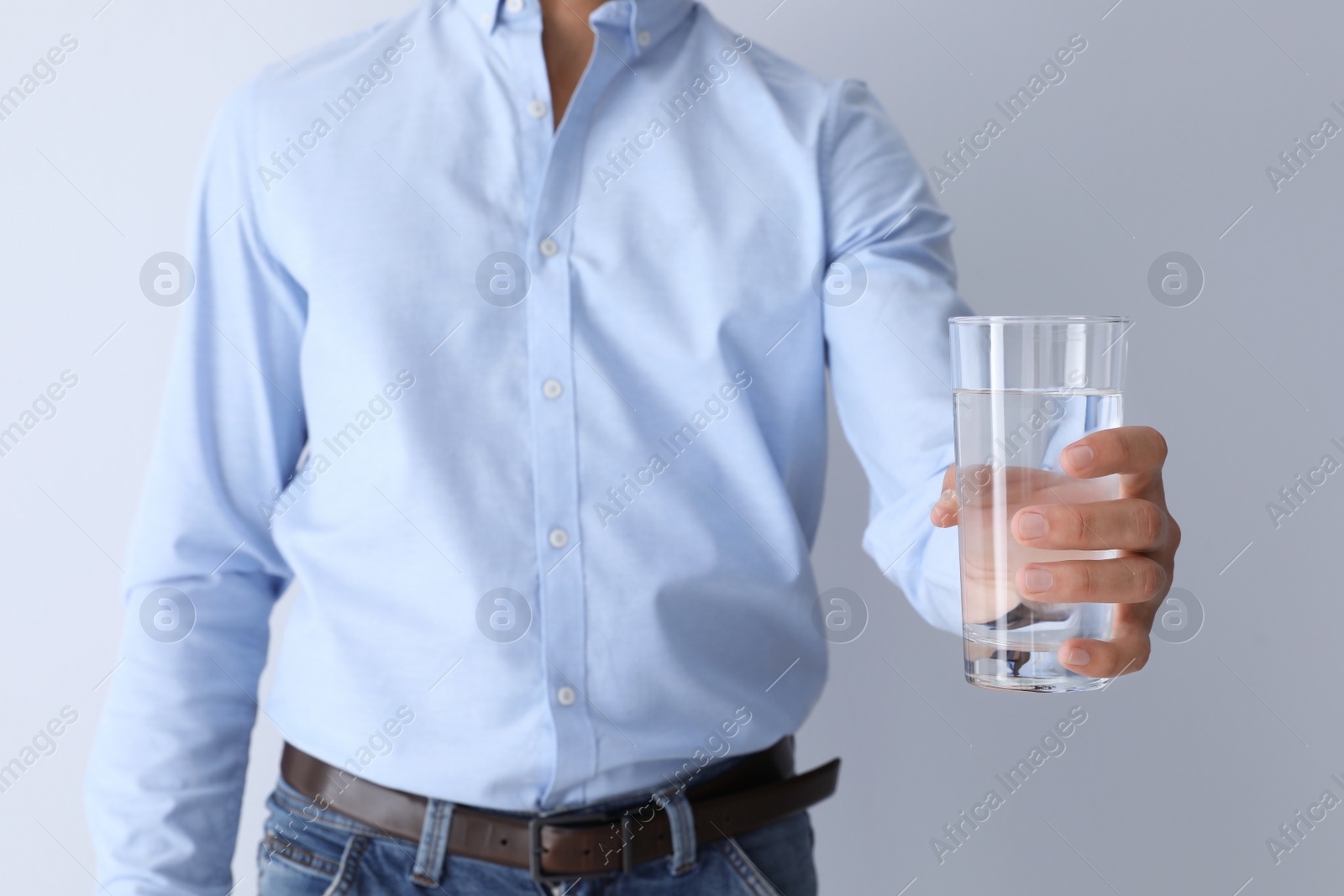 Photo of Man holding glass of pure water on white background, closeup