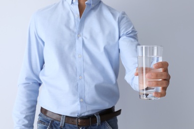 Photo of Man holding glass of pure water on white background, closeup