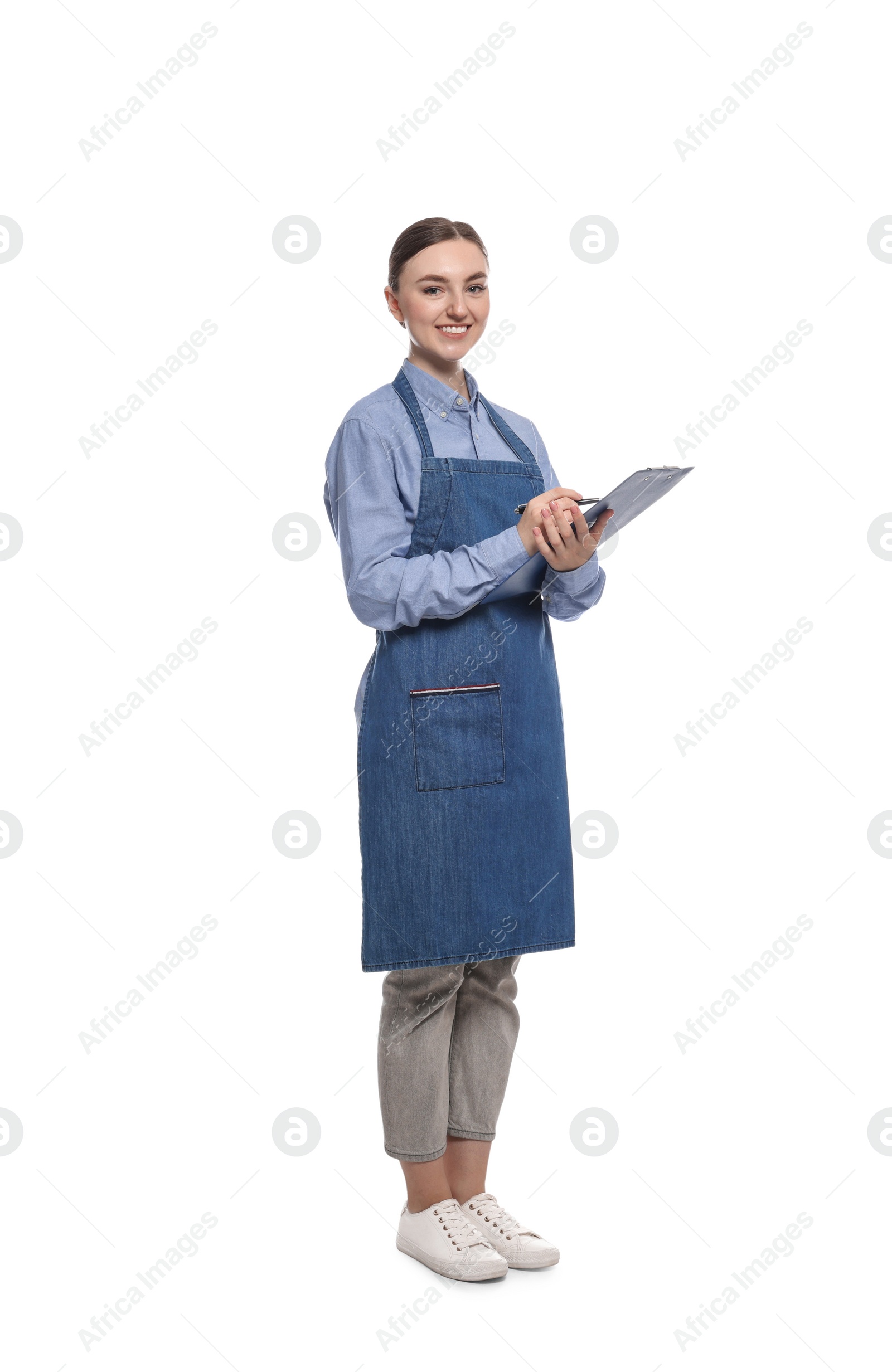 Photo of Beautiful young woman in clean denim apron with clipboard on white background