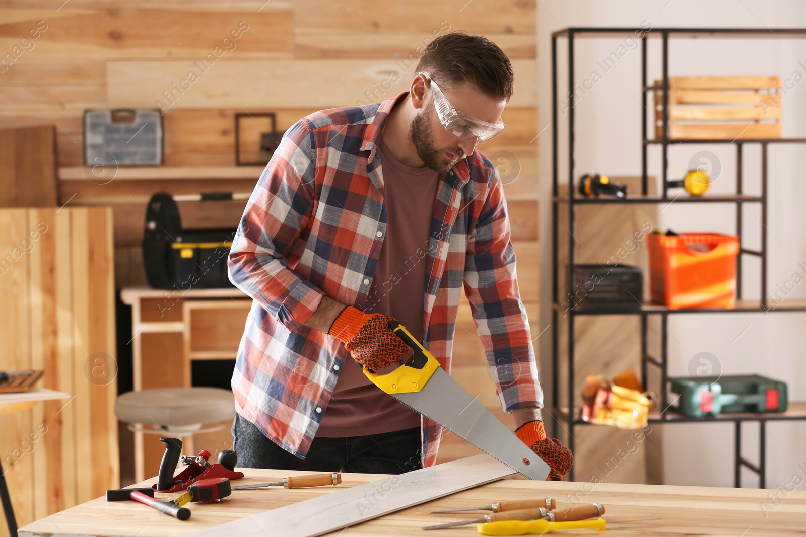 Photo of Carpenter sawing wooden plank at table in workshop