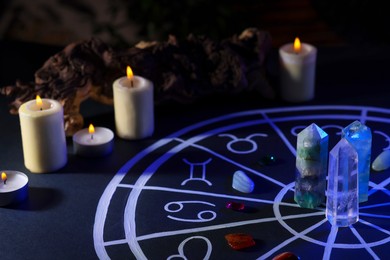 Natural stones for zodiac signs, drawn astrology chart and burning candles on black table. Color tone effect