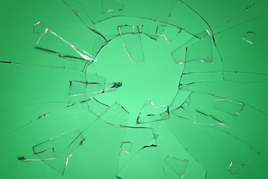 Image of Broken glass with cracks on green background