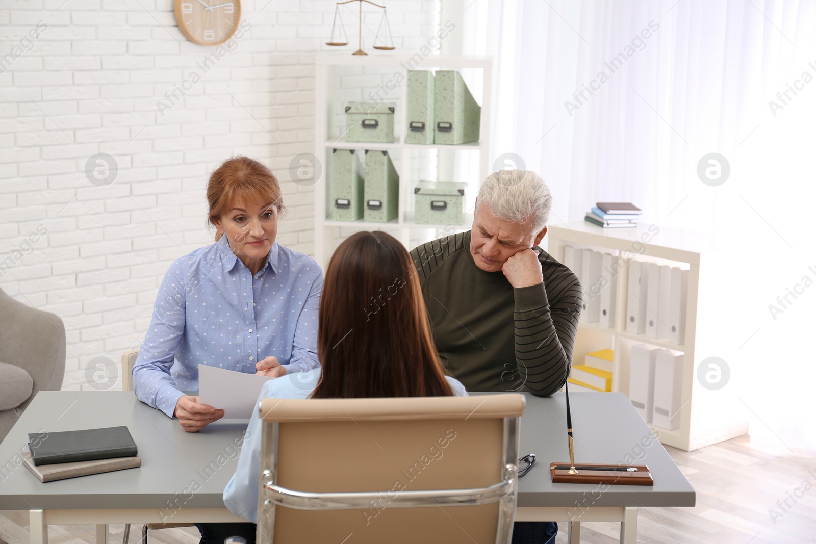 Photo of Young lawyer consulting senior couple in office