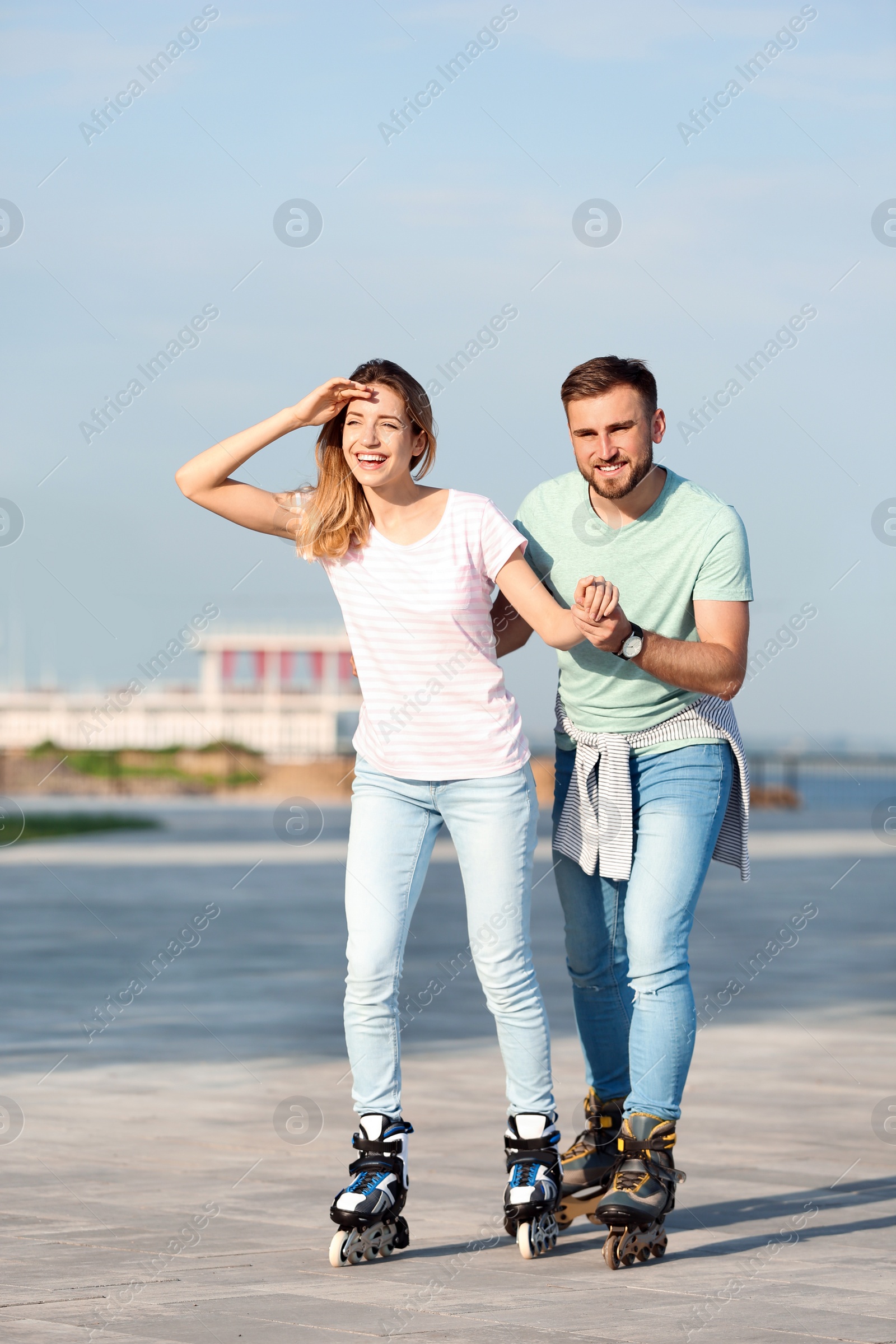 Photo of Young happy couple roller skating on city street