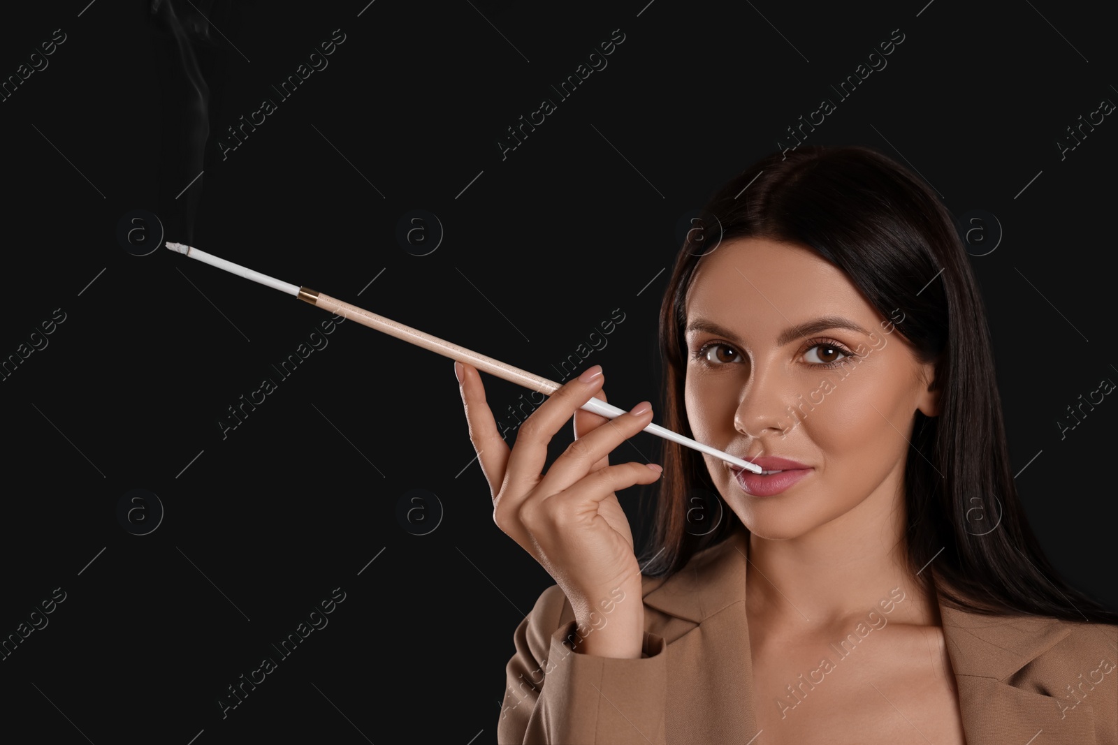 Photo of Woman using long cigarette holder for smoking on black background