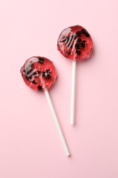 Sweet colorful lollipops with berries on pink background, flat lay