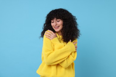 Photo of Happy young woman in stylish yellow sweater on light blue background