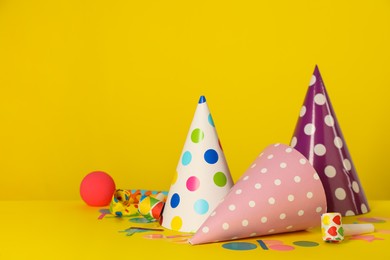 Photo of Colorful party hats and festive items on yellow background. Space for text