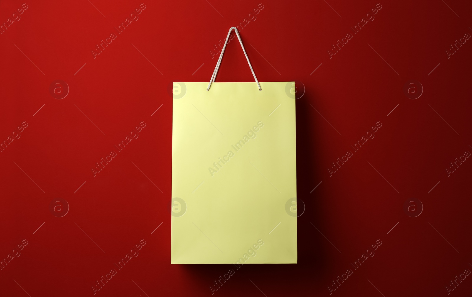 Photo of Paper shopping bag hanging on red background