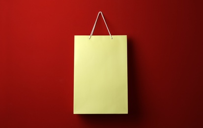 Photo of Paper shopping bag hanging on red background