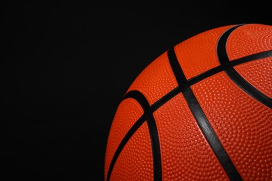 Photo of One basketball ball on black background, closeup. Space for text