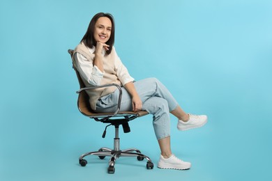 Photo of Mature woman sitting in comfortable office chair on turquoise background