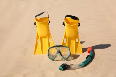 Pair of flippers, snorkel and diving mask on sandy beach