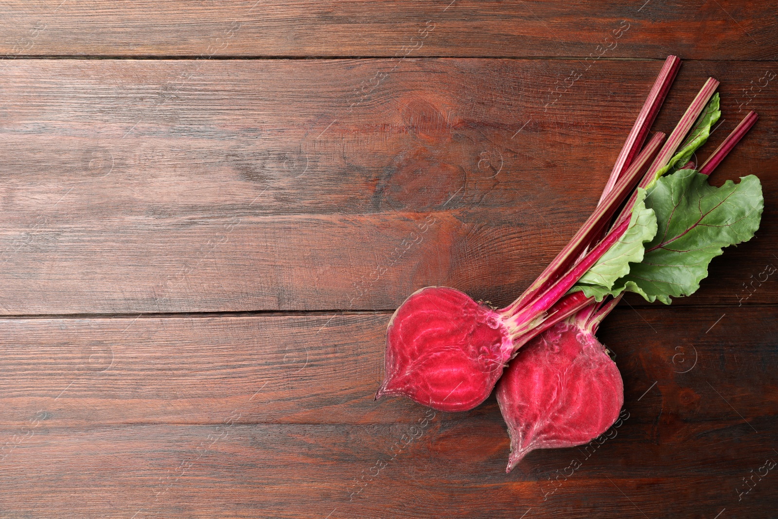 Photo of Halves of raw beet on wooden table, flat lay. Space for text