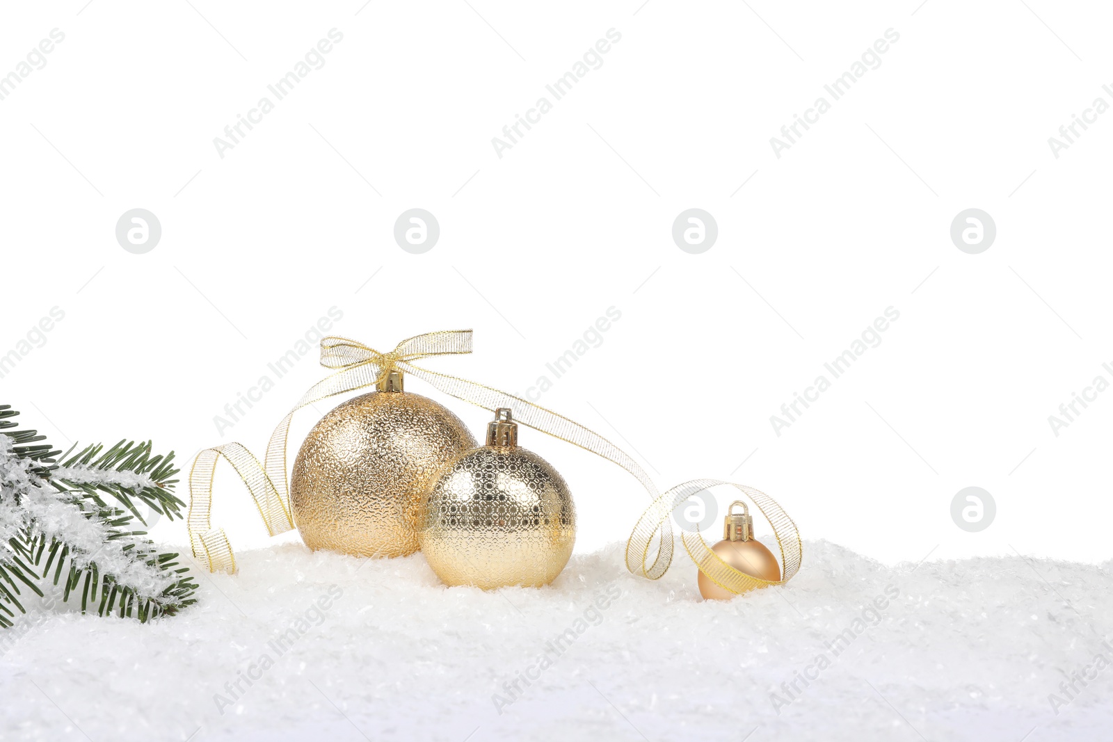 Photo of Beautiful golden Christmas balls with bow and fir tree branch on snow against white background