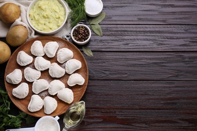 Photo of Raw dumplings (varenyky) and ingredients on brown wooden table, flat lay. Space for text