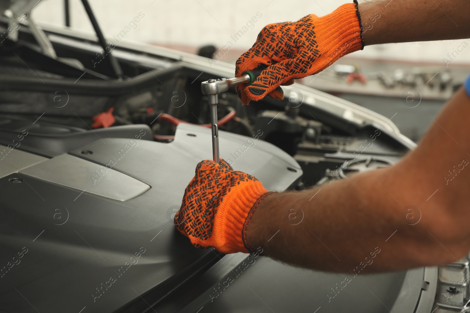 Photo of Professional mechanic fixing modern car at automobile repair shop, closeup