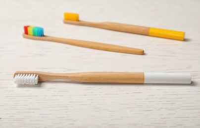 Photo of Eco bamboo toothbrushes on white wooden table