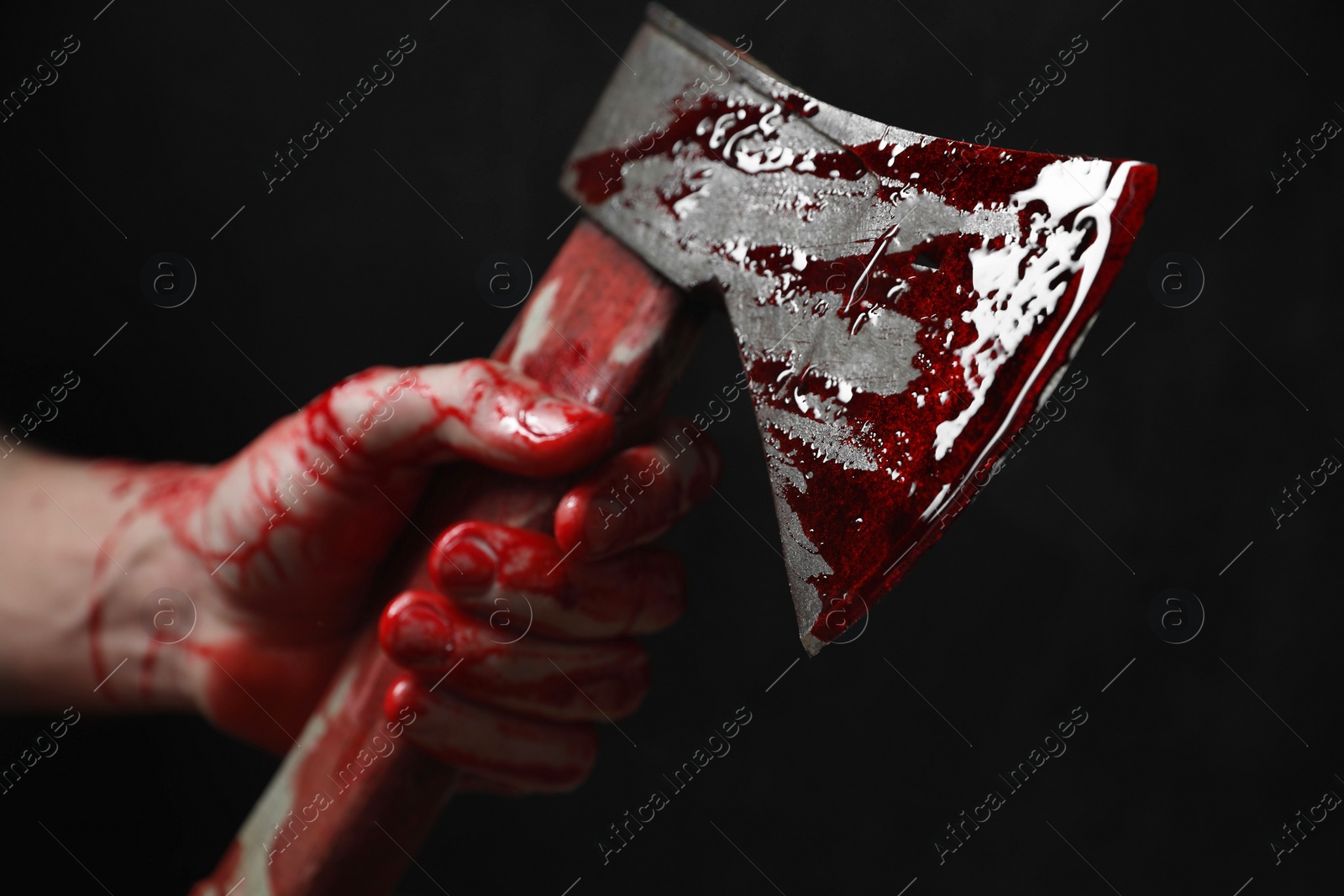 Photo of Man holding bloody axe on black background, closeup