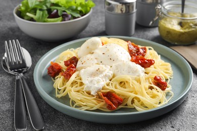 Photo of Delicious spaghetti with burrata cheese and sun dried tomatoes on grey table