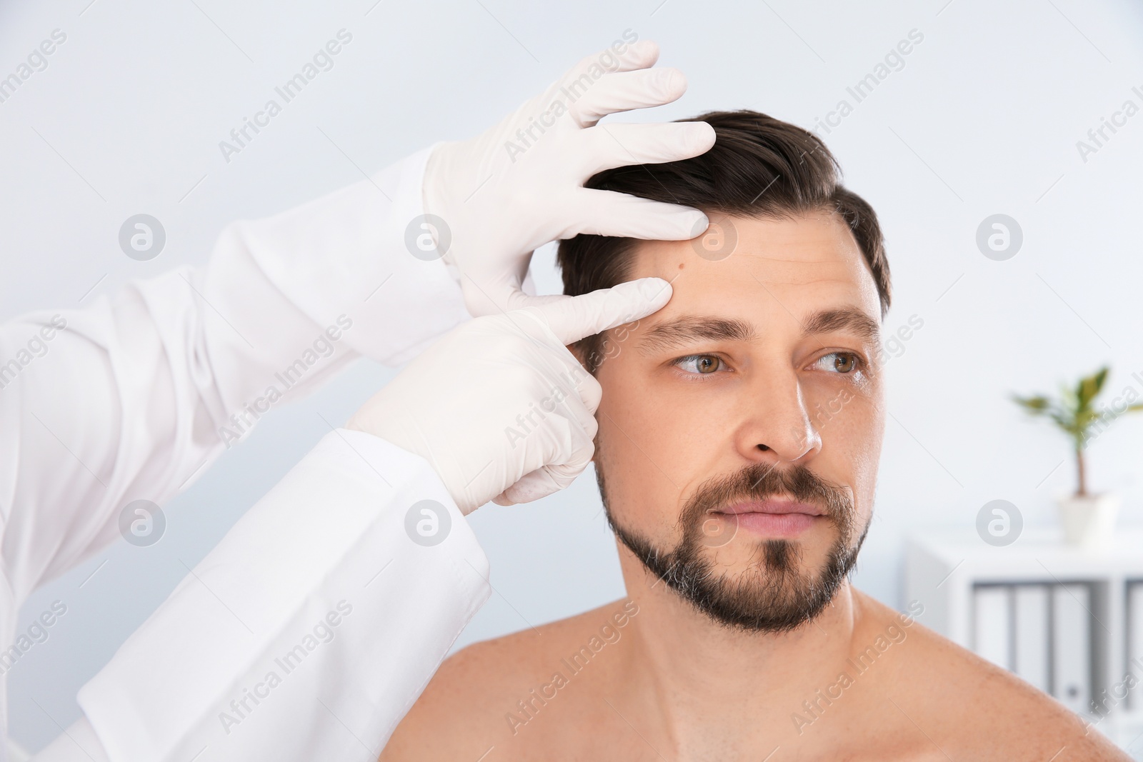 Photo of Dermatologist examining patient's birthmark in clinic