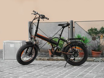 Modern electric bicycle near black metal fence outdoors