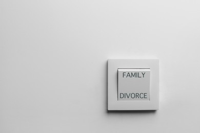Light switch with words Family and Divorce on white wall, space for text