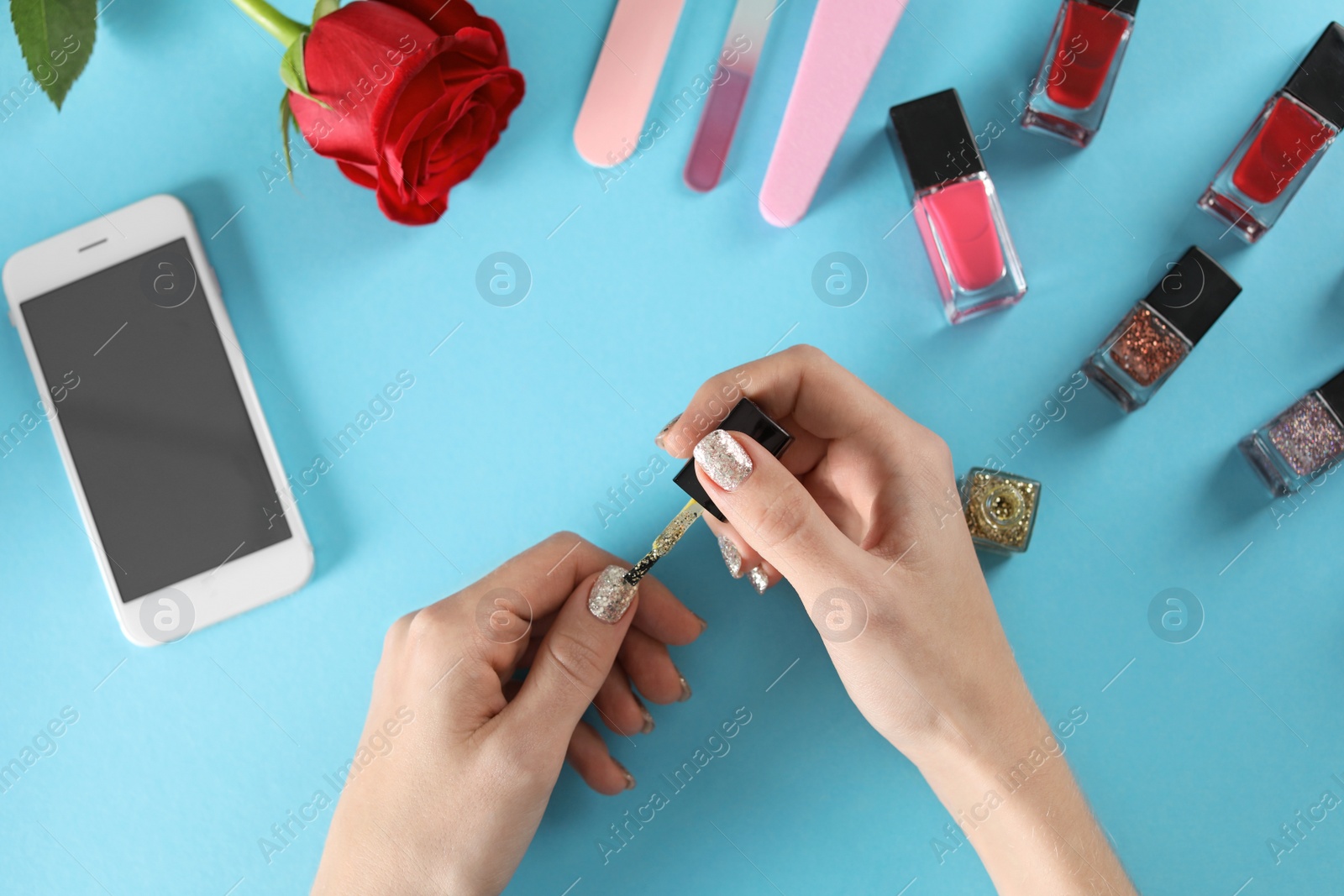 Photo of Woman applying nail polish on color background, top view