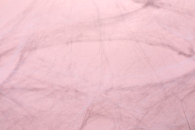 Photo of Creepy white cobweb on pink background, closeup