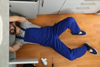 Male plumber repairing kitchen sink, top view