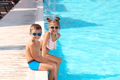 Photo of Cute little children sitting near swimming pool