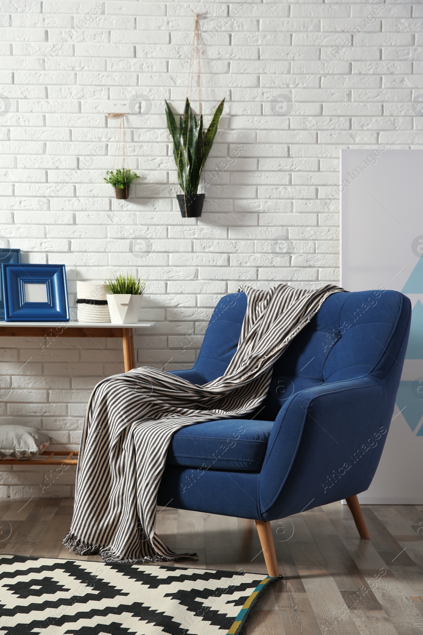 Photo of Modern interior with cozy armchair and table near brick wall