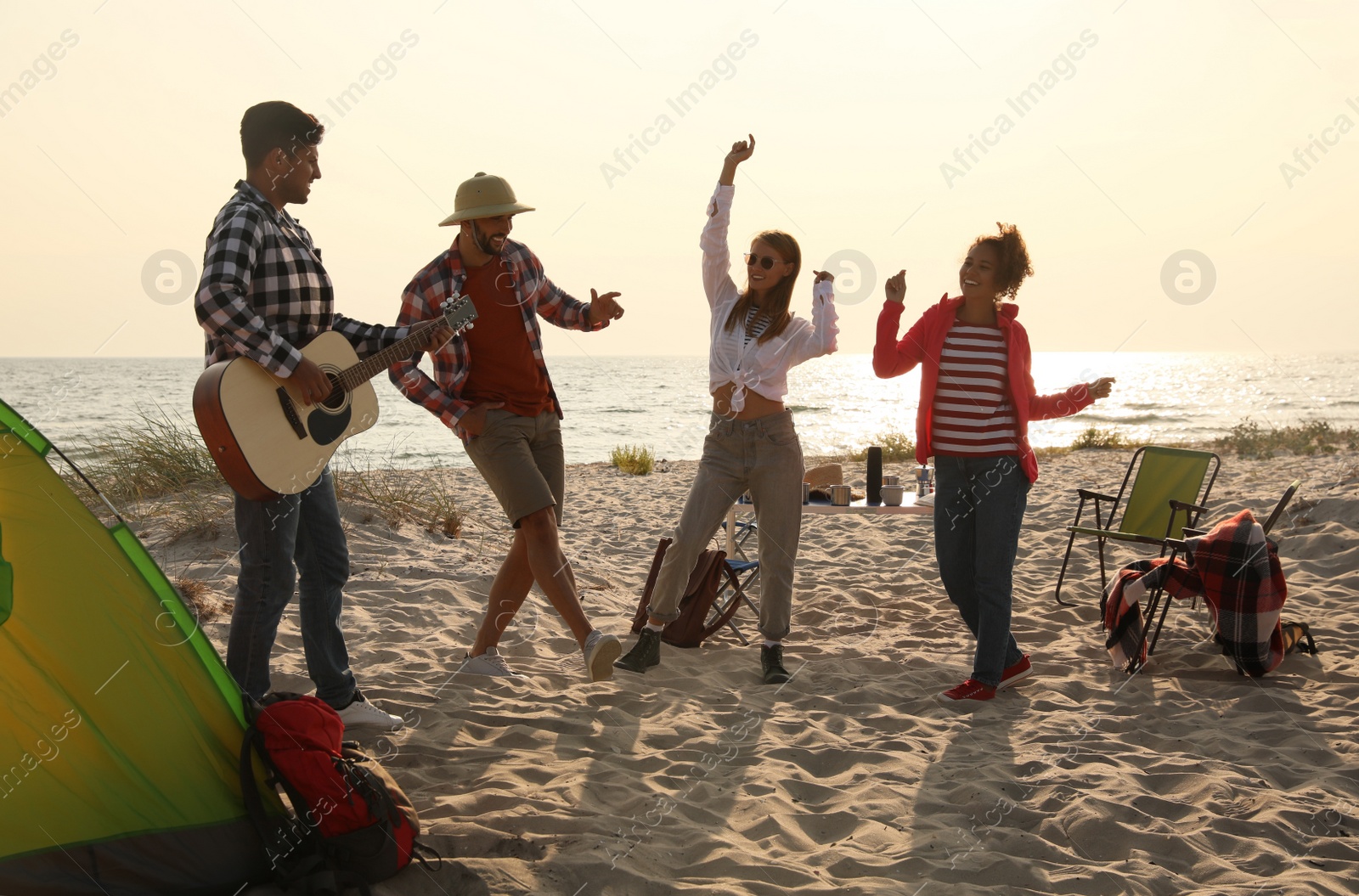 Photo of Friends having party near camping tent on sandy beach
