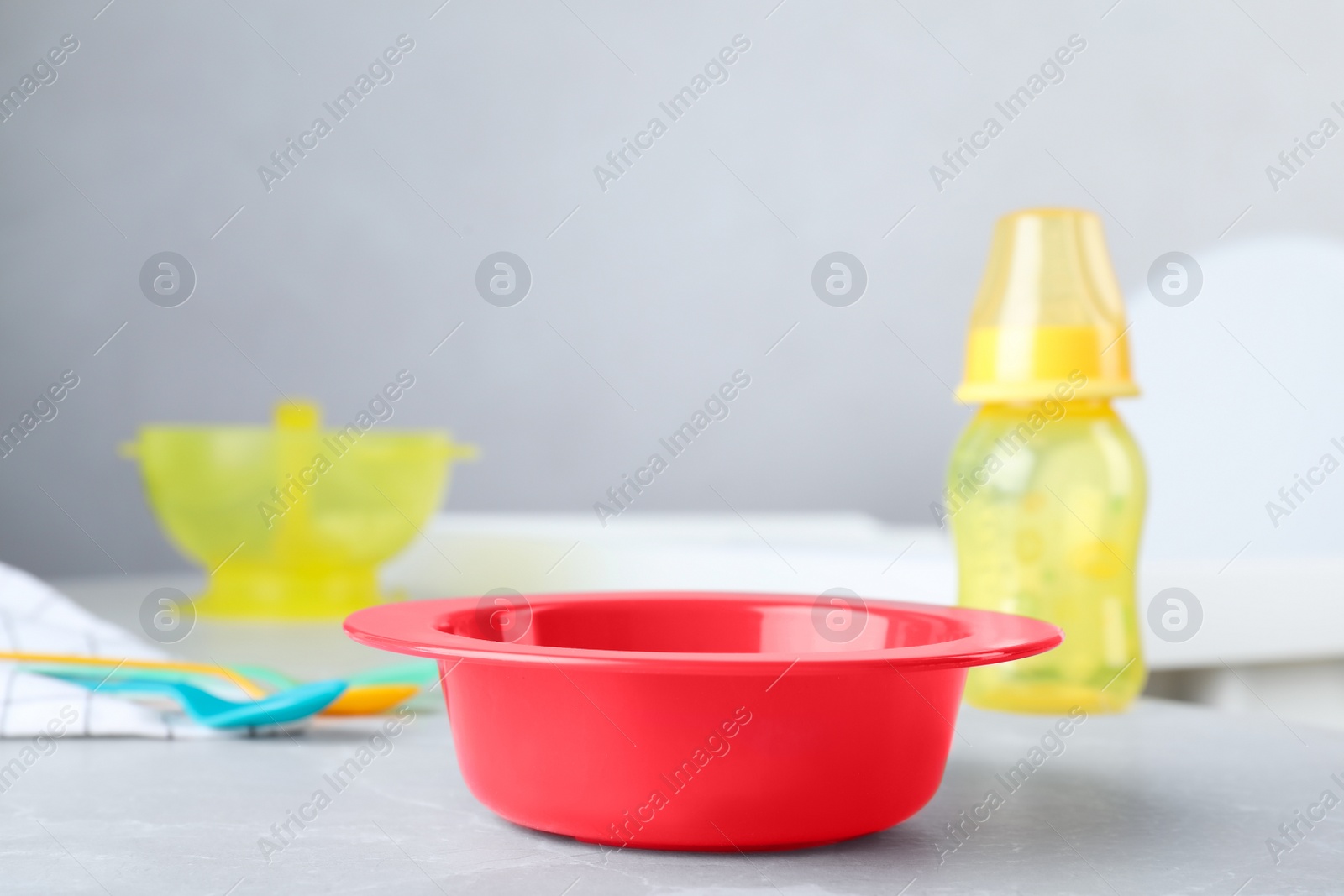 Photo of Red plastic bowl on grey marble table indoors, space for text. Serving baby food