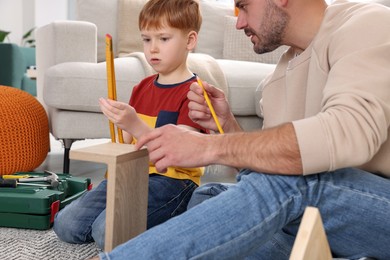 Father and son measuring shelf together at home. Repair work