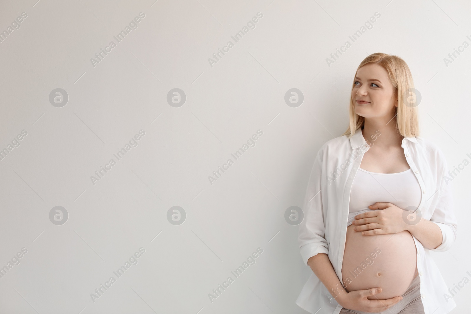 Photo of Portrait of beautiful pregnant woman on light background. Space for text