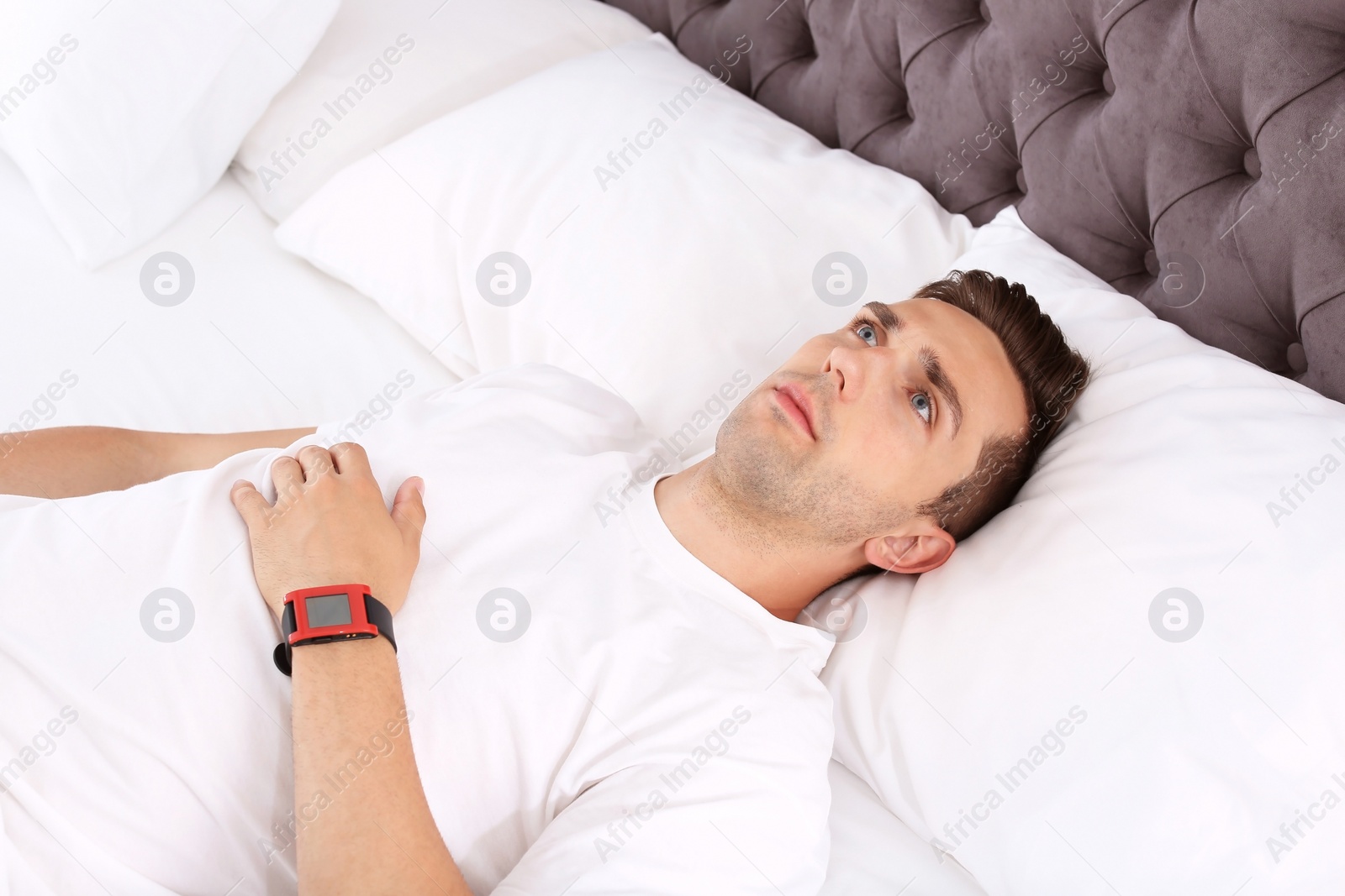 Photo of Young man lying in bed at home. Sleep disorder