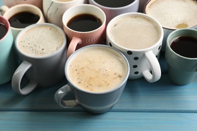 Many cups of different coffee drinks on light blue wooden table