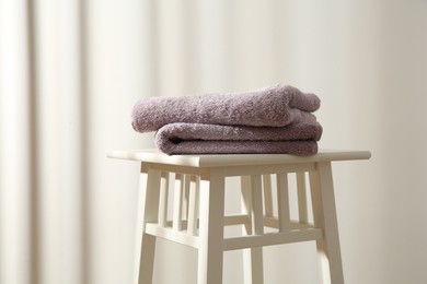 Photo of Violet towels on stool indoors. Space for text